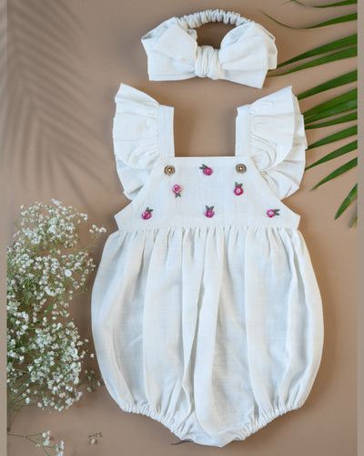 A cute romper with some flower embroidery on it with matching hair accessory, some leaf and flower aside.