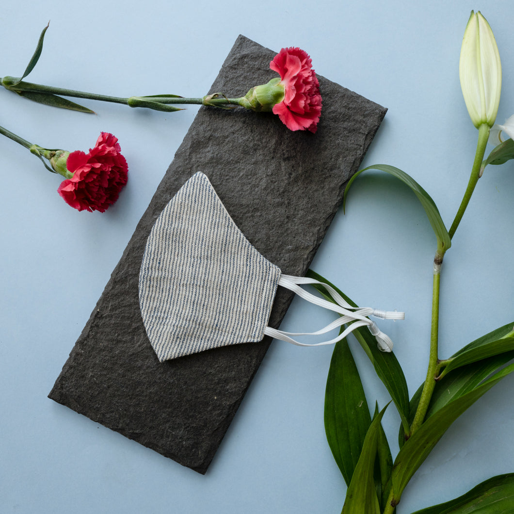 An adjustable mask kept on a grey sheet with some flowers aside.
